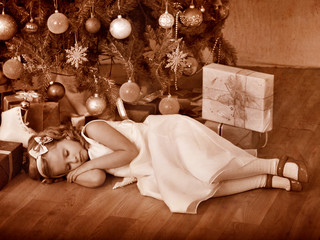 Child sleeping near Christmas tree.