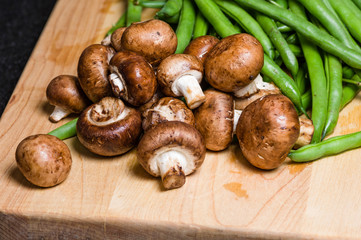 Mushrooms and green beans on a wooden board