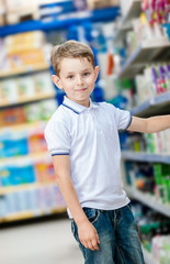 Little boy chooses cosmetics on the shelves of the shop