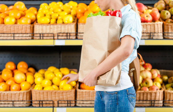 Choosing lemons girl hands bag with fresh vegetables in the shop