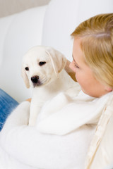 Close up of woman in white sweater embracing white white puppy 
