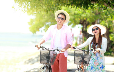 Young couple portrait with bicycle on the beach