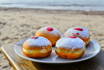 Festive donuts with jam on sandy beach