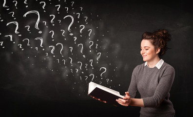 Pretty woman reading a book with question marks coming out from