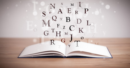 Opened book with flying letters