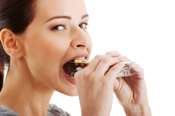 Casual beautiful woman trying to eat blister of pills.