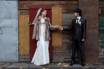 Image of a bride and a groom standing near the building and looking at each other.