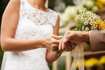 Obraz na płótnie Canvas Bride puts ring on groom's finger