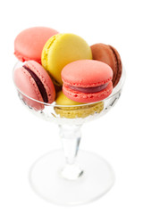 Colorful macaroons in glass vase on white background