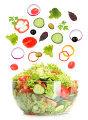 Fresh mixed vegetables falling into bowl of salad isolated