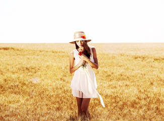 Portrait of beautiful young woman with poppies in the field