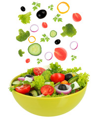 Fresh mixed vegetables falling into bowl of salad isolated