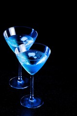 two glasses of fresh blue cocktail with ice on wood table