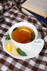 Cup of tea with ginger on plaid with a book