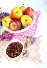 Juicy apples on plate on white wooden table