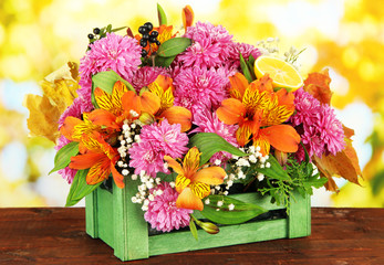 Obraz na płótnie Canvas Flowers composition in crate on table on bright background
