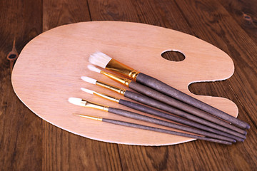 Wooden art palette and brushes on table close-up