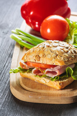 Fresh ham sandwich on wooden board - close up