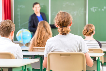 Lehrer unterrichtet an Tafel Klasse in Schule