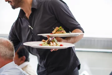 Foto op Plexiglas Ober met een bord met saladeschotel op een bruiloft. © Irina Schmidt