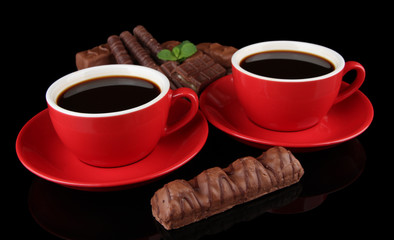 Red cups of strong coffee and chocolate bars isolated on black