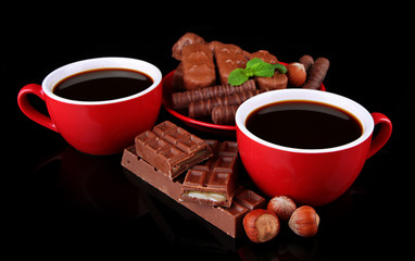 Red cups of strong coffee and chocolate bars isolated on black