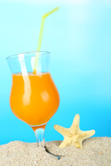 Beach cocktail in sand on blue background