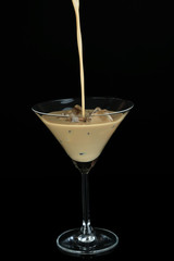 Pouring liquor in glass isolated on black