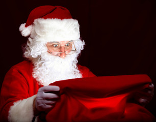Santa sitting at the Christmas room and looking into the sack