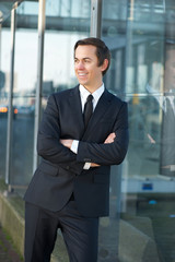 Happy businessman smiling outdoors with arms crossed