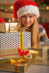 Obraz na płótnie Canvas Happy girl in santa hat with stack of christmas present boxes