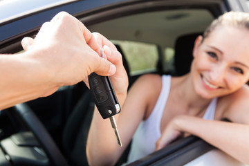 junge frau im neuen auto schlüssel übergabe lachend