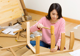 Asian woman assembling chair by hammer