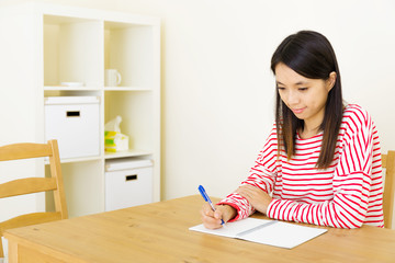 Asian woman writing on notebook