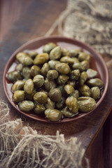 Pickled capers, rustic wooden background, studio shot