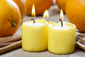 Obraz na płótnie Canvas Beautiful candles and juicy oranges on jute table cloth