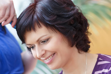 stylist prepares hairstyle for beautiful woman