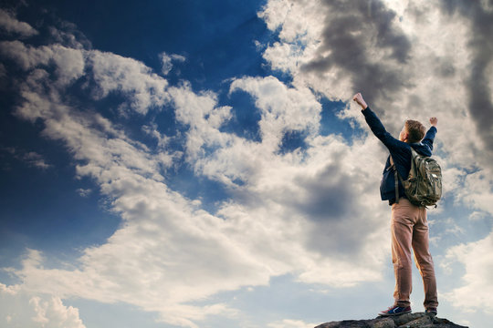 Man with victory gesture on the top of mountain