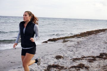 Fit young woman jogging on sea shore
