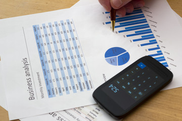 senior businessman holding a pen, analyzing blue charts