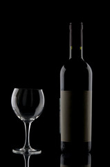 Wine bottle and goblet on black backdrop
