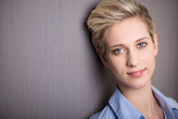 junge frau lehnt entspannt an grauer wand