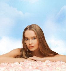 Obraz na płótnie Canvas beautiful woman with long hair and rose petals
