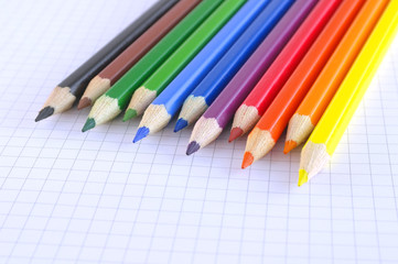 Color pencils on the checked paper of notepad
