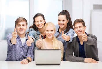 Fototapeta premium smiling students with laptop showing thumbs up