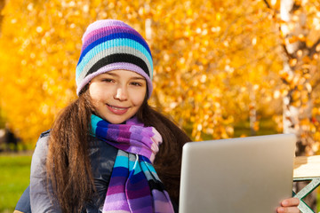 Girl in the autumn park with tablet