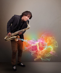 Obraz na płótnie Canvas Attractive musician playing on saxophone with colorful abstract