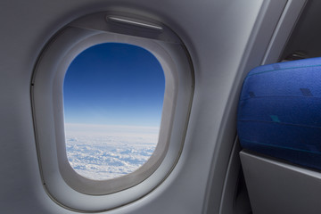 airplane window with wing and cloudy sky behind