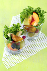 Fruit salad in glasses, on wooden background