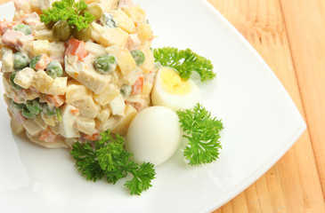 Russian traditional salad Olivier, on wooden background